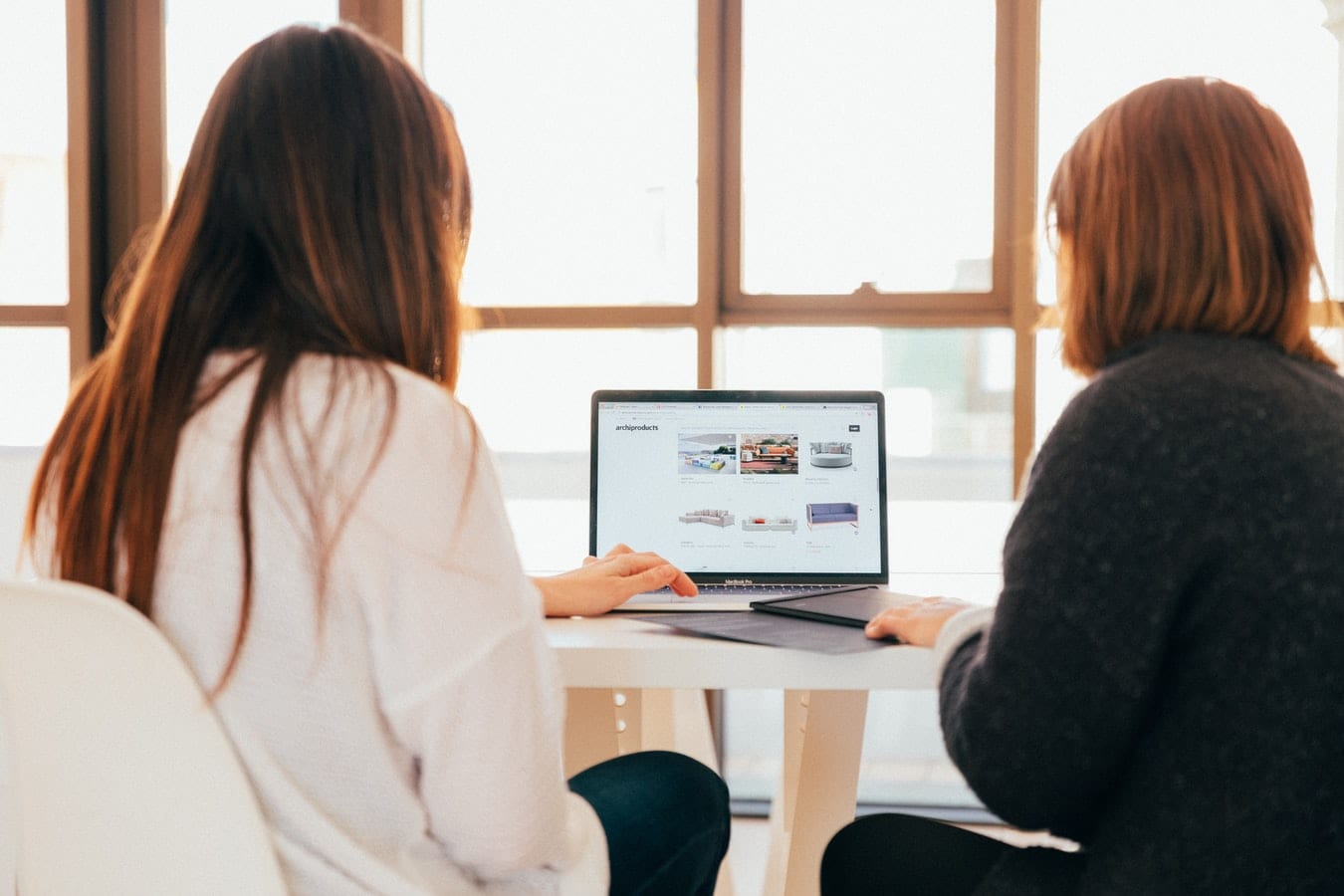 Two women side by side looking at a laptop screen representing display advertising.
