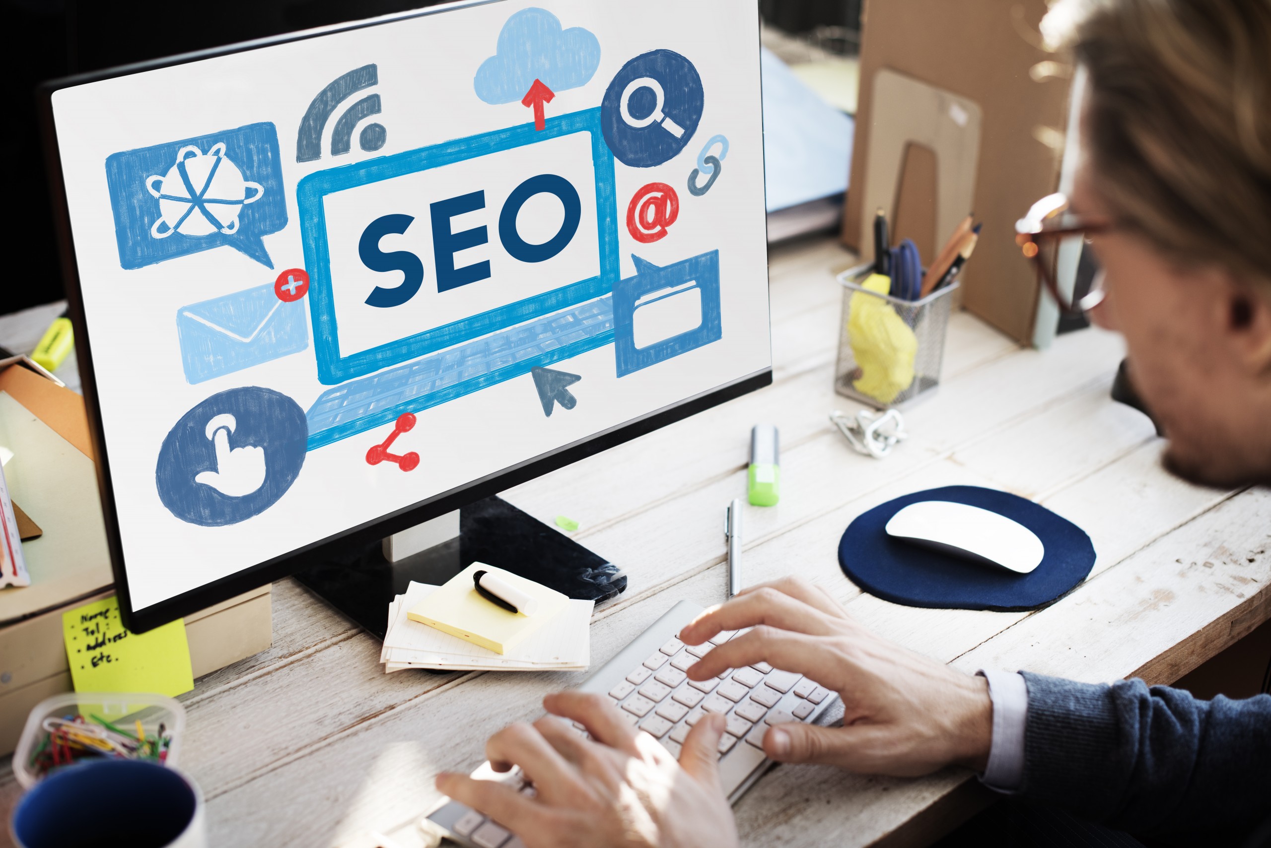 Man typing in front of desktop computer screen that says "SEO" representing installing the best SEO plugins.