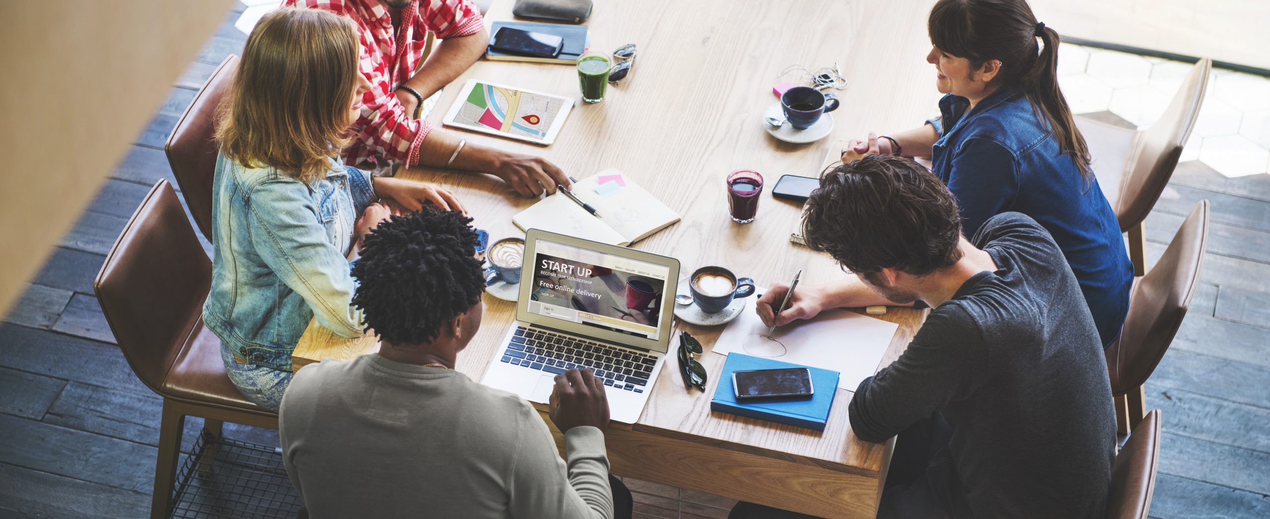 Group of people sitting at a table in a meeting discussing website issues.