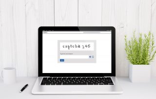 Laptop on white desk with CAPTCHA code on laptop screen. CAPTCHA has long been the golden standard to prevent bot submissions on website forms.