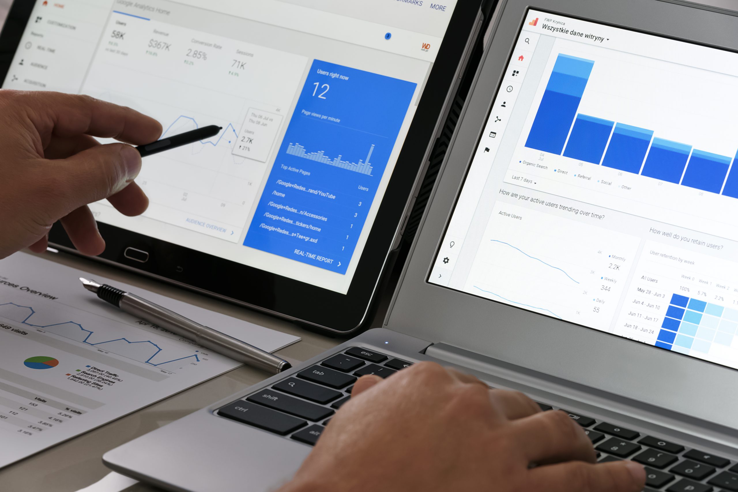 Man using a laptop and tablet side by side to analyze Google Analytics data