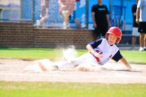 Youth baseball player sliding home. Website homepage sliders are loved by clients but can be detrimental to website usability and conversions.