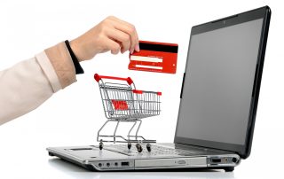 Laptop with small shopping cart and a hand with credit card symbolizing online shopping.