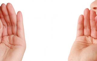 Woman's hand cupped over ear listening while another woman whispers