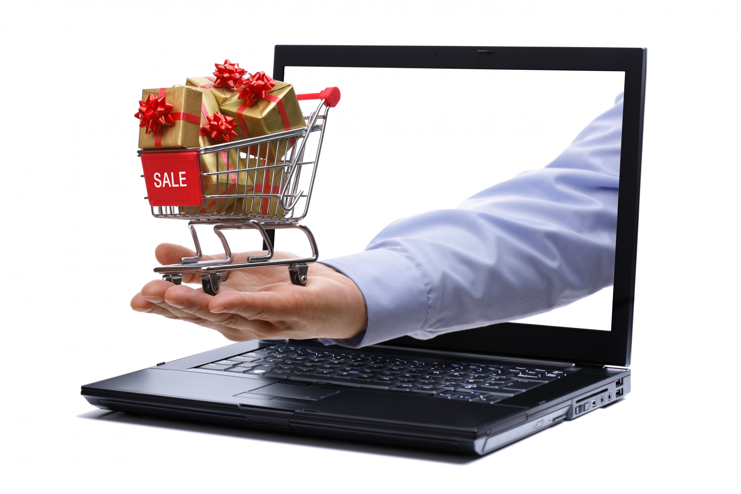 Man's hand holding tiny shopping cart full of holiday gifts through a laptop screen representing holiday digital marketing.