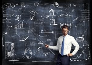 Image of teacher in front of blackboard to represent the task of getting small business owners to understand digital marketing