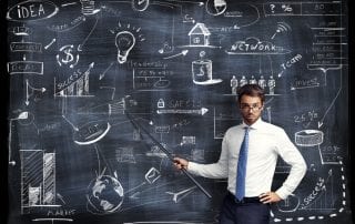 Image of teacher in front of blackboard to represent the task of getting small business owners to understand digital marketing