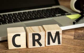Laptop keyboard behind three wooden blocks that have the letters "CRM".