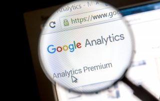 Magnifying glass showing Google Analytics Analytics Premium on computer screen signifying Google Analytics For Small Businesses.