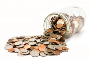 Coins spilling out of a glass jar, signifying running a marketing program with a significantly reduced budget.