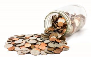 Coins spilling out of a glass jar, signifying running a marketing program with a significantly reduced budget.