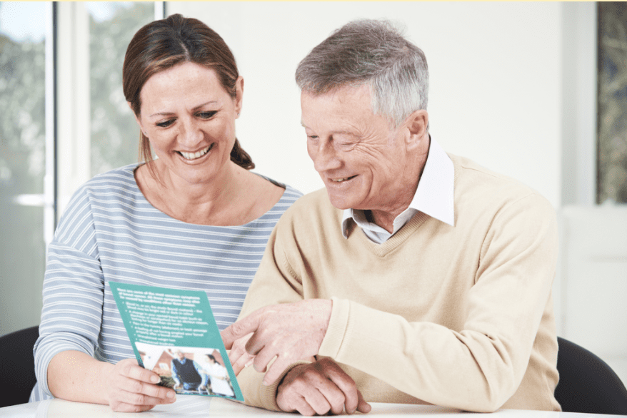 Adult daughter and senior father reviewing a brochure for an assisted living community.