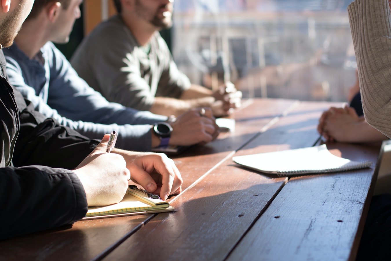 Team of people sitting at a table to discuss website issues signaling the need for a website audit.