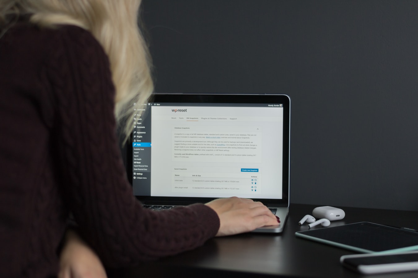 Woman facing away from camera sitting on laptop working on a WordPress website.